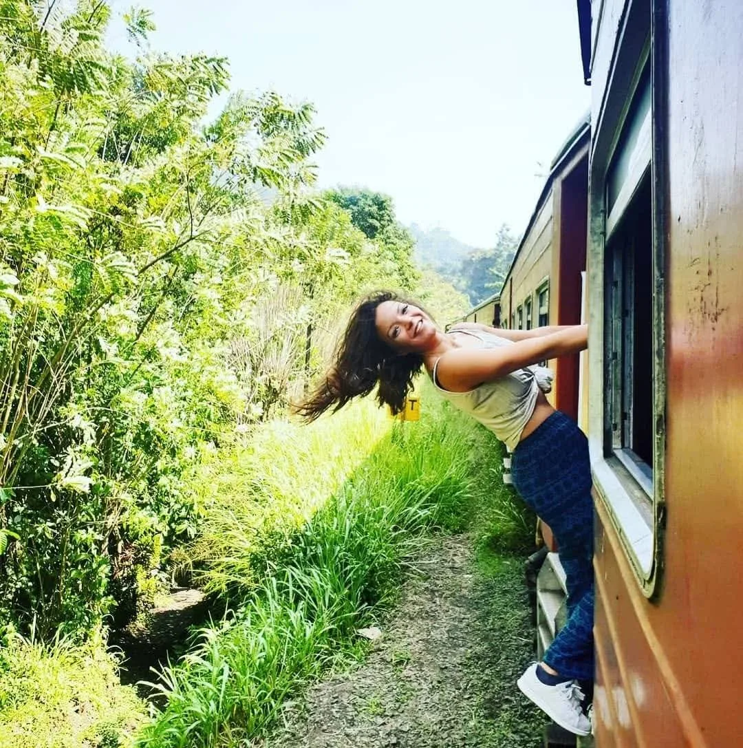Sara Nordanger smiler og henger ut av et tog i Sri Lanka