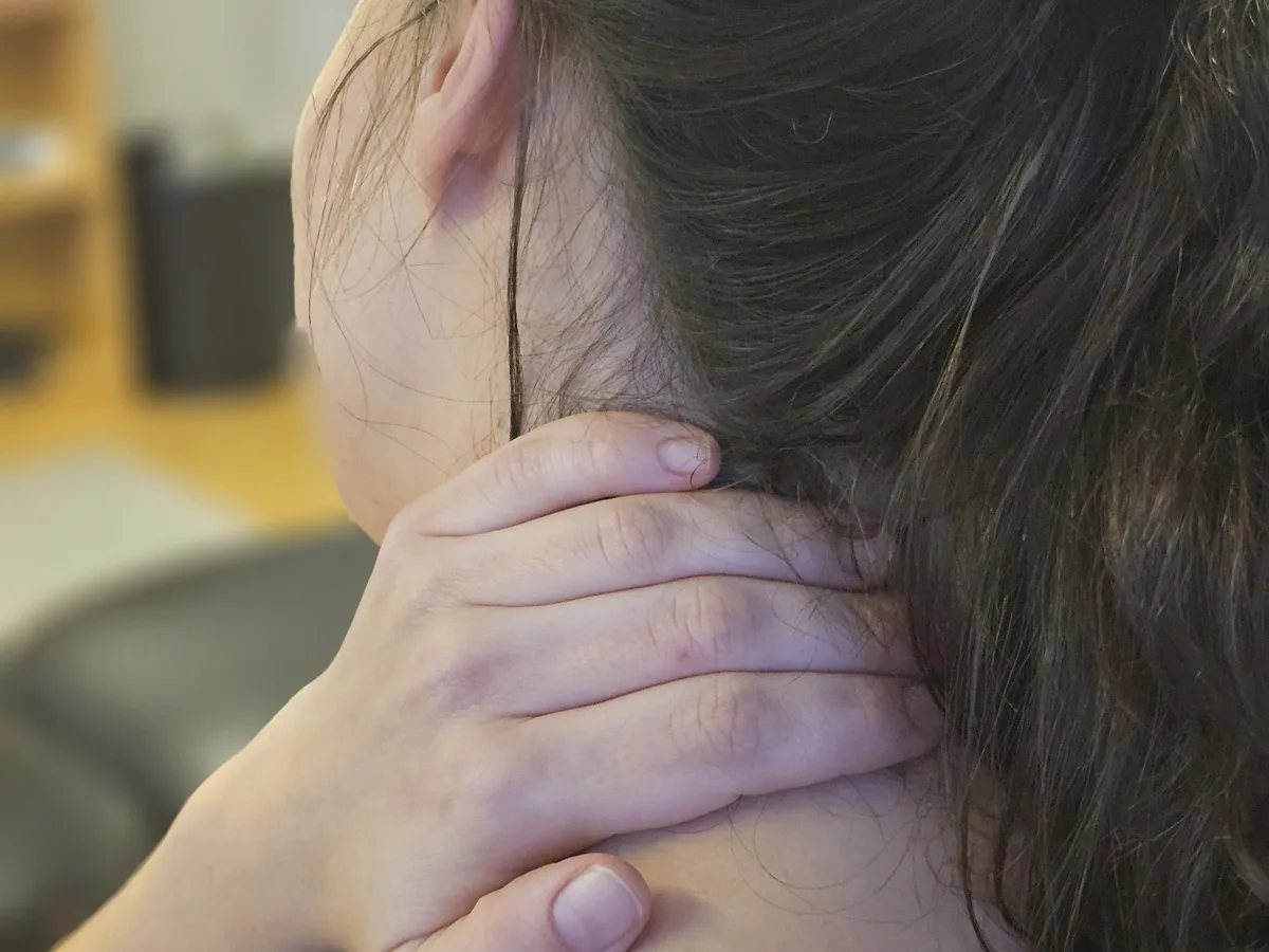 Kvinne som holder seg på nakken